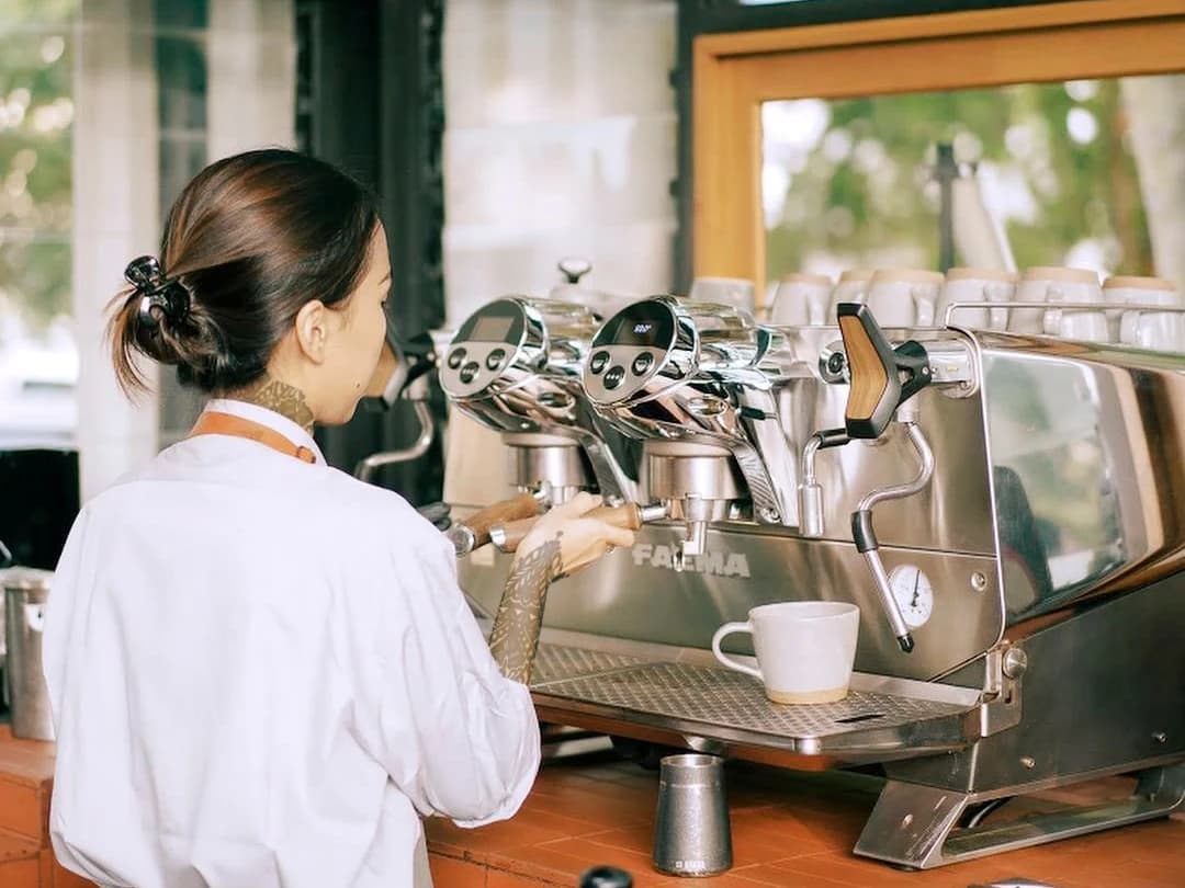 Barista preparando espresso en una máquina Faema instalada en una cafetería