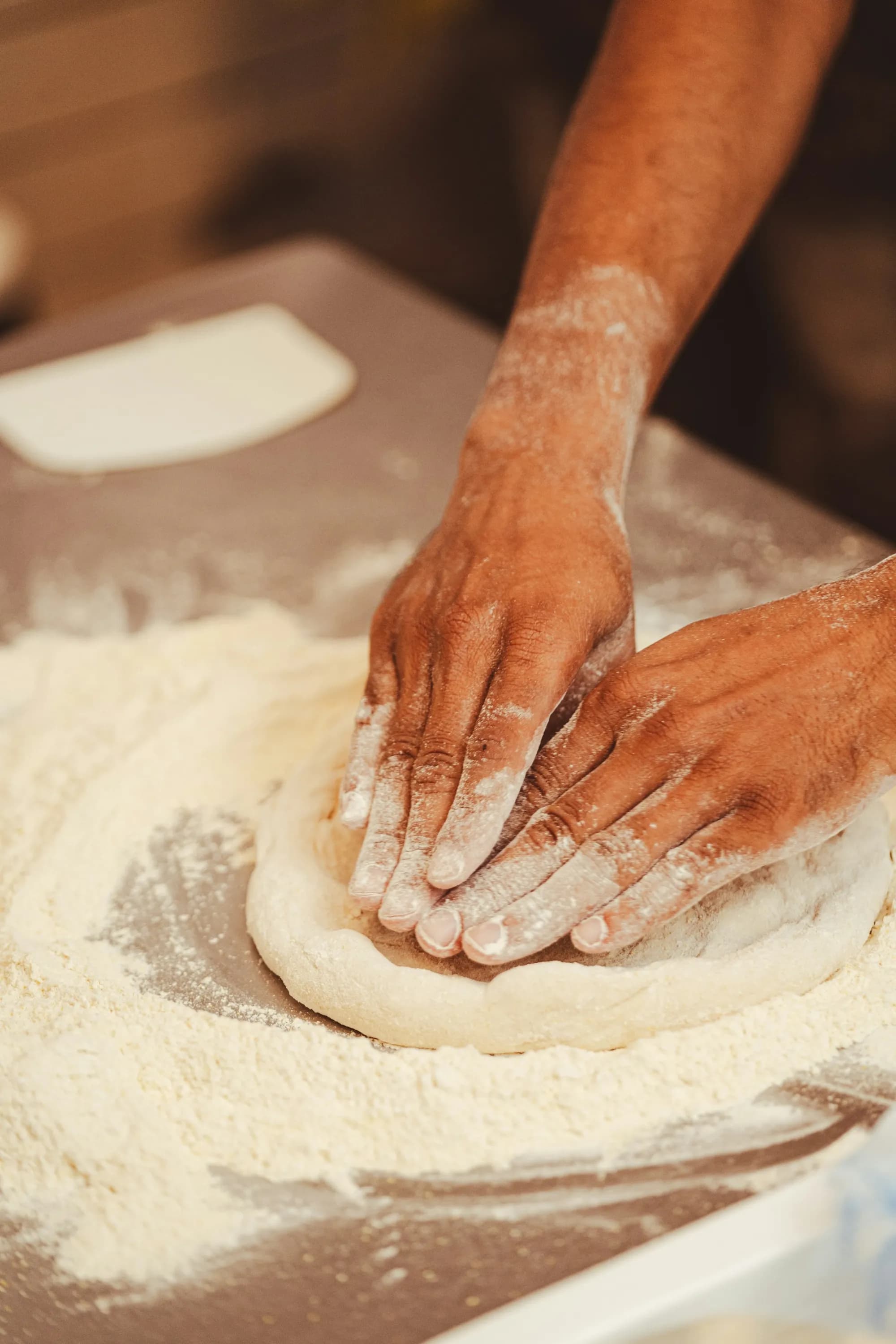 Manos estirando una masa de pizza sobre harina