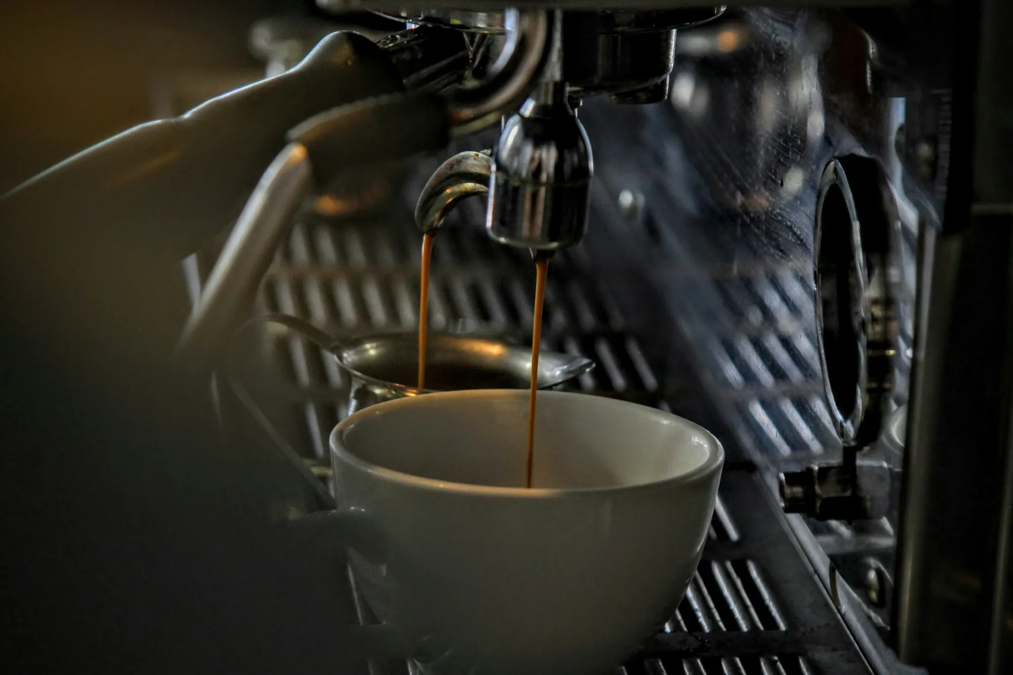 Espresso cayendo en una taza bajo el grupo de una máquina profesional