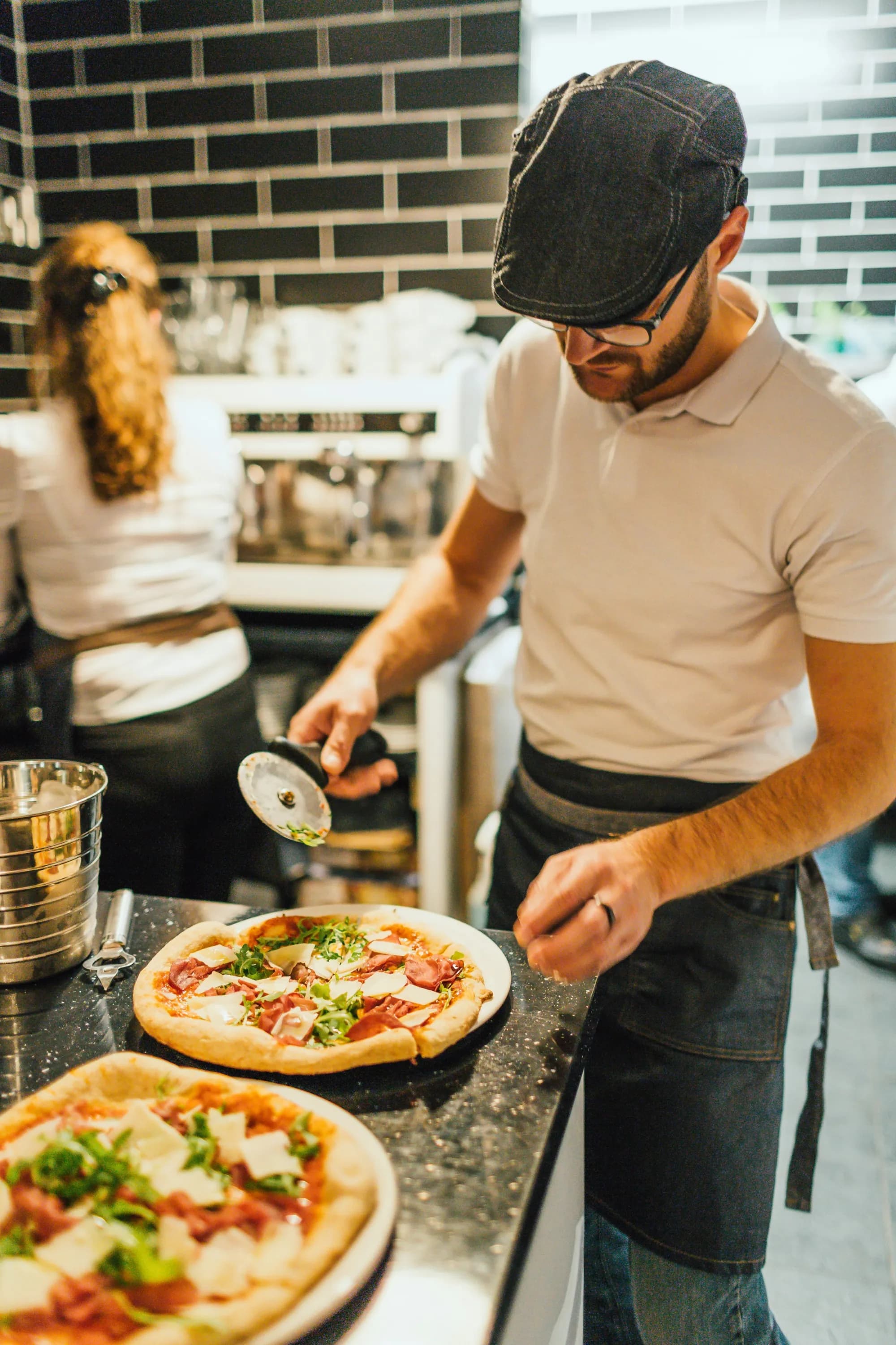 Pizzaiolo preparando pizzas en una cocina abierta